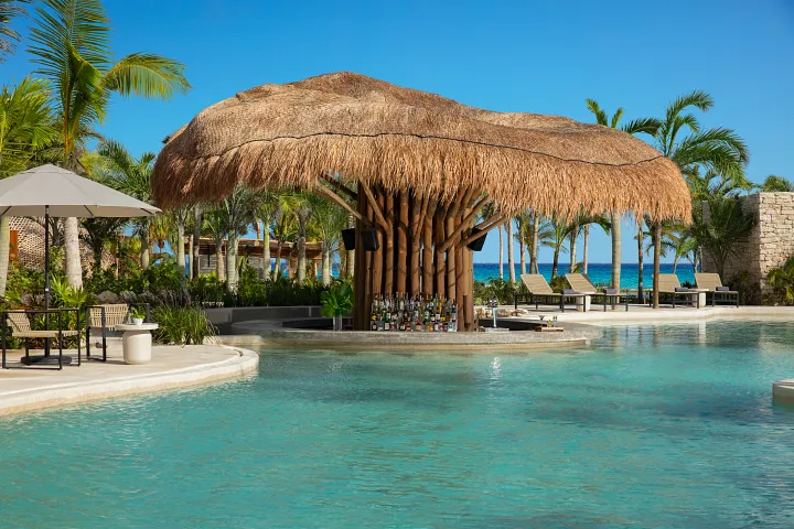 Mantarray Swim-Up Bar at Secrets Moxché Playa del Carmen featuring a tropical thatched-roof bar in a lagoon-style pool with ocean views.