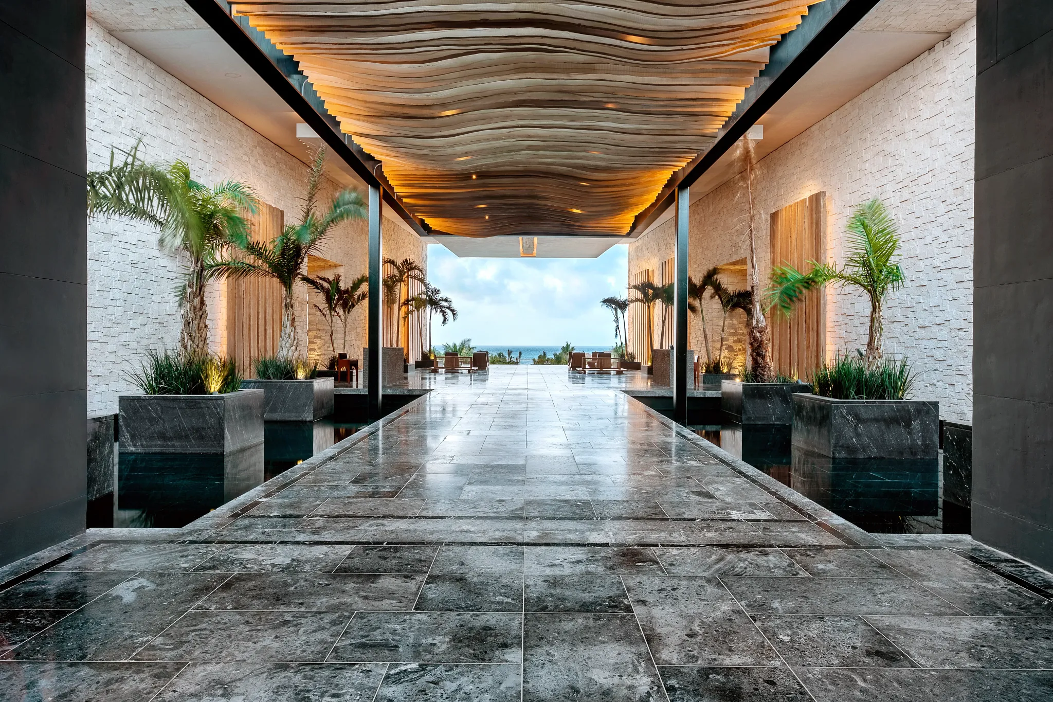Elegant resort entrance corridor with illuminated ceiling and ocean views at Secrets Moxché Playa Del Carmen.