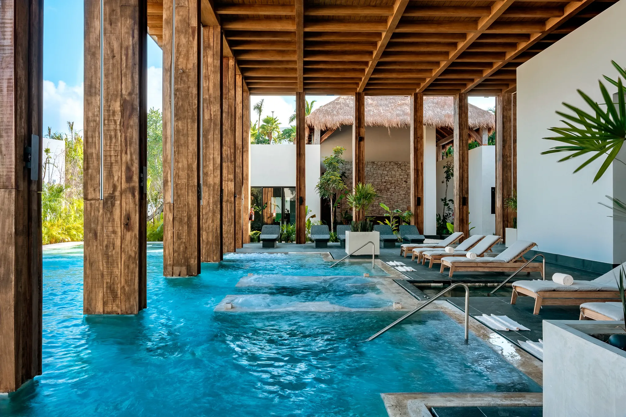 Hydrotherapy pool with lounge chairs and wooden architecture at the Secrets Spa by Pevonia at Secrets Moxché Playa Del Carmen.